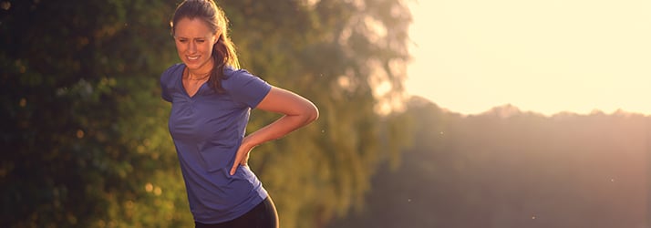 woman holding back on jog route