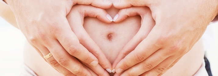 Man and woman with hands on womb of expecting